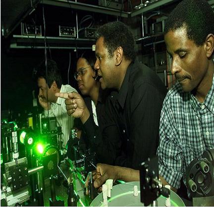 Anthony Johnson explaining a laser setup with other African-American students surrounding him.