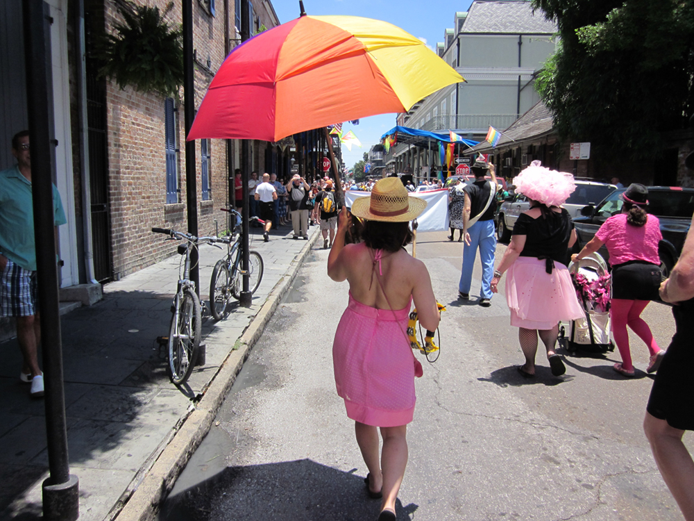 A woman walking down the street with a rainbow umbrella is shown here.