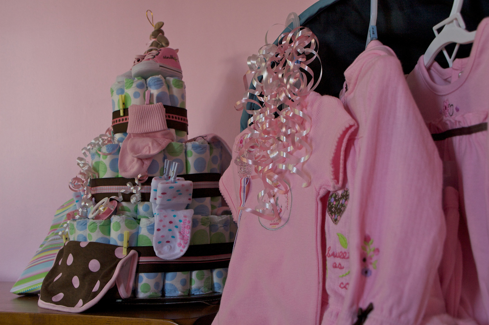 Pink baby clothes and other baby shower gifts are shown here.